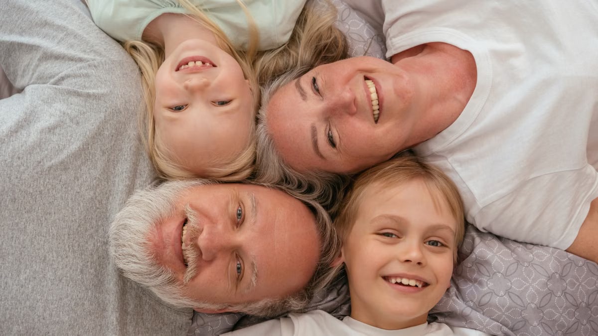 A joyful multigenerational family lying down and smiling together, displaying warmth and affection.
